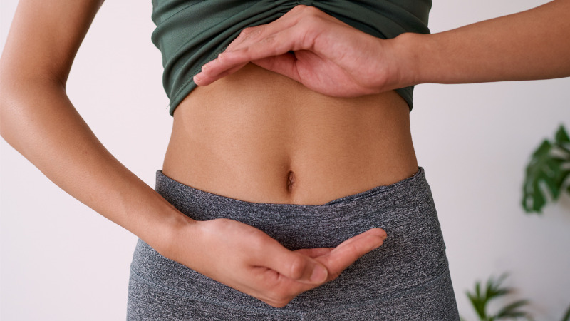 Close up of a multi ethnic woman's stomach cupped by her hands.